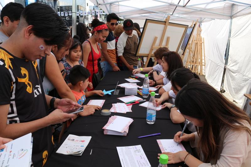 Voluntarios escribiendo nombres en coreano para los asistentes del “Día de Corea” en Buenos Aires.